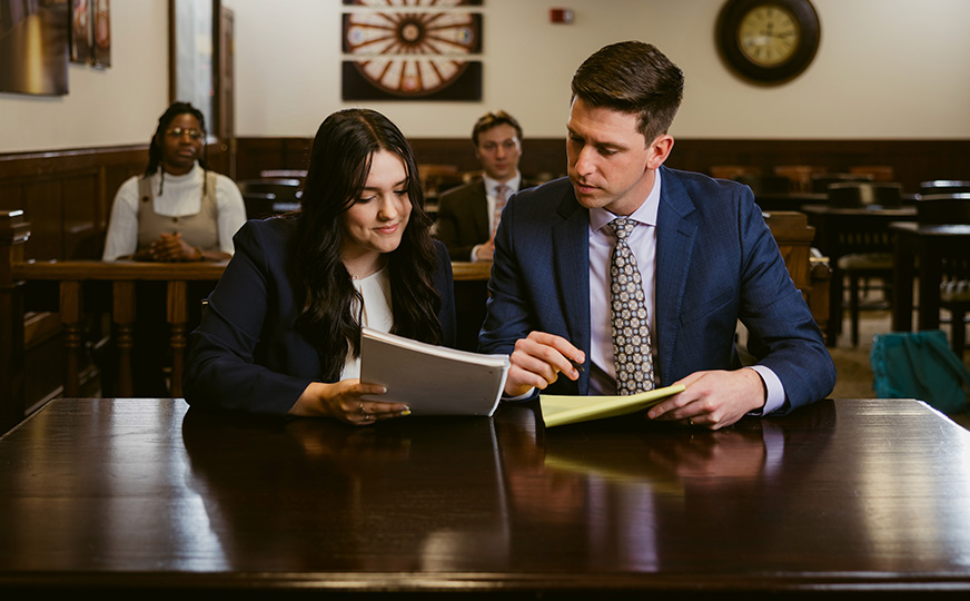 Two ONU law students reviewing briefs and preparing arguments in a courtroom setting.